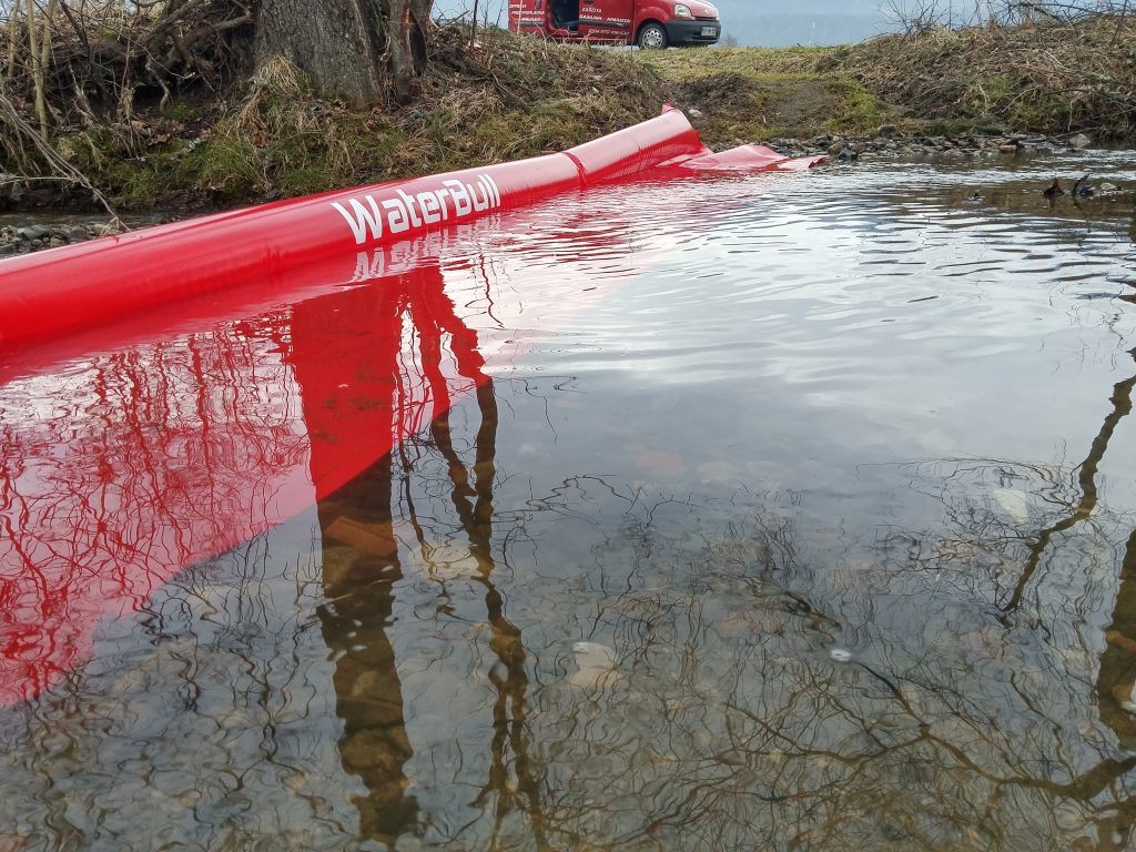 Rdeča mobilna protipoplavna pregrada WaterBull ob vodi